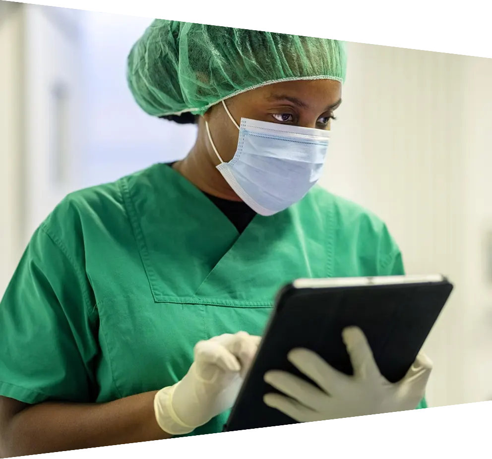 Female African nurse wearing scrubs using digital tablet in operating room