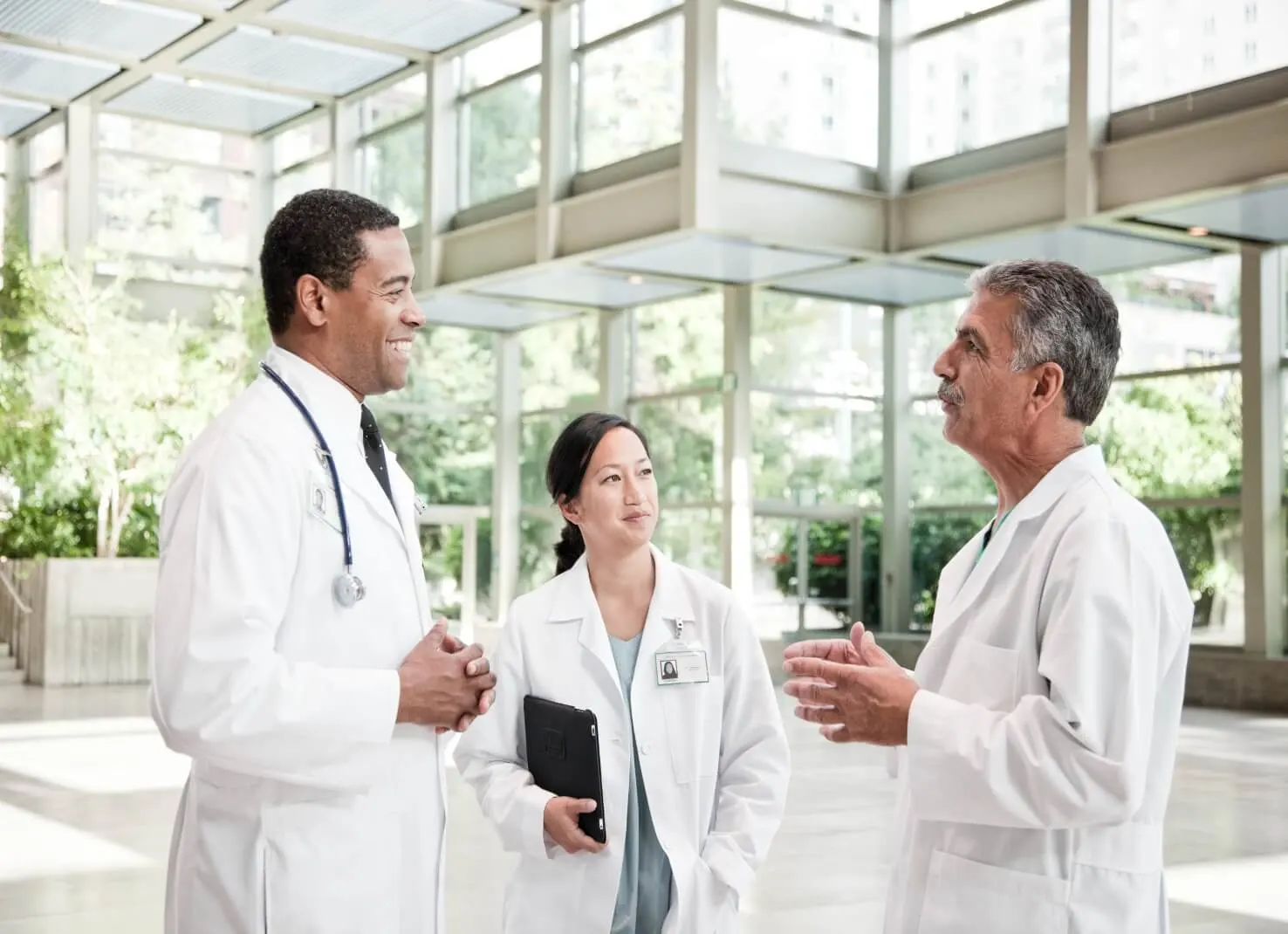 Mixed race group of doctors meeting in lobby of large hospital