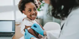 Doctor putting a bandage on the child's arm after the vaccine