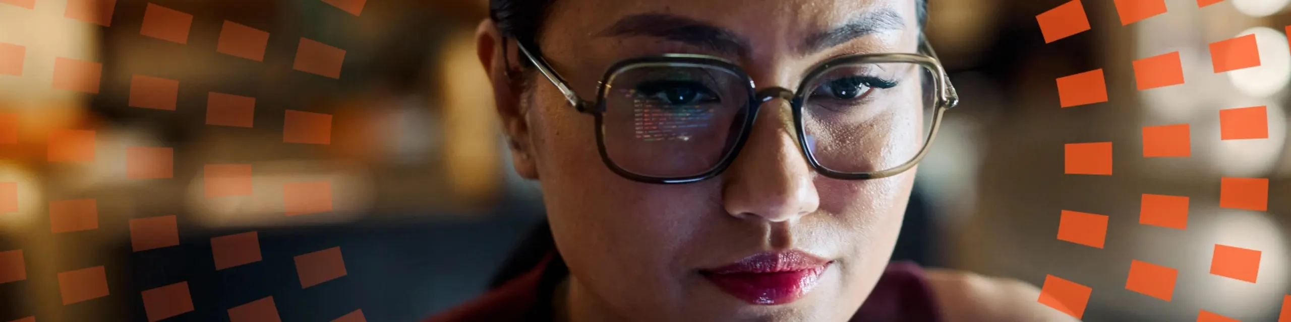 A woman with eyeglass looking at a screen with a reflection of it on the eyeglass