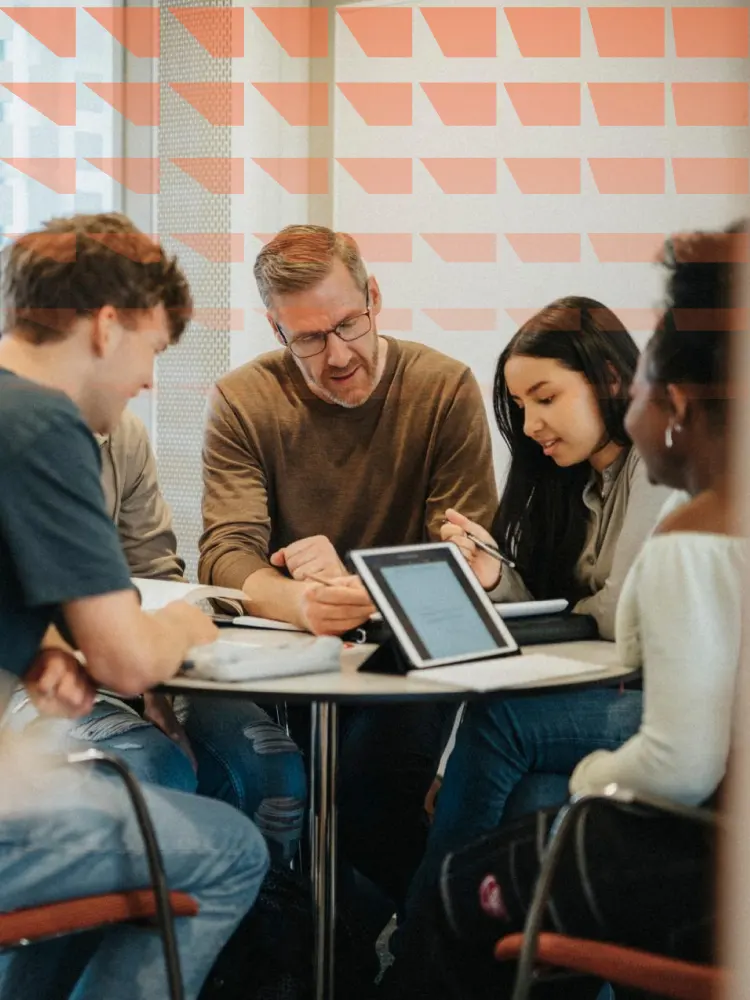 Mature male professor explaining students at table in university
