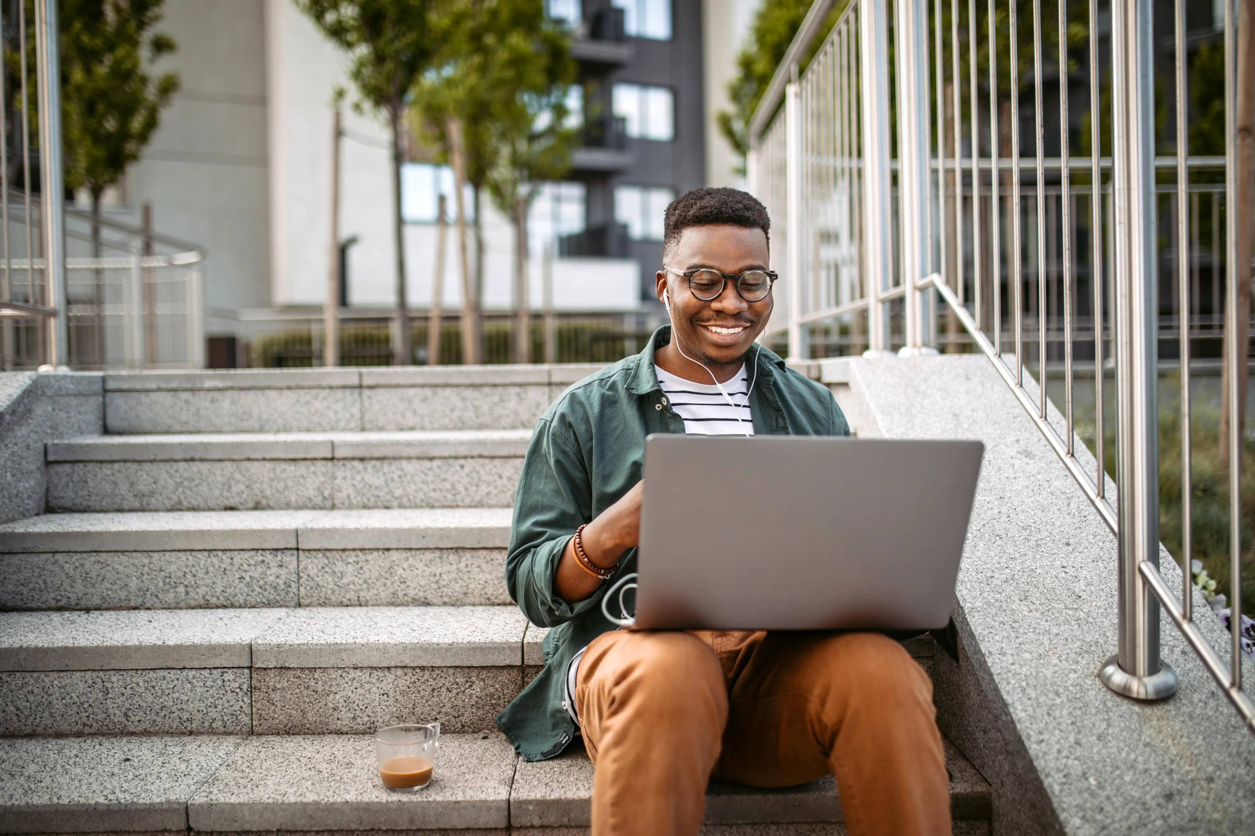 man working on laptop while sitting on stairs outside