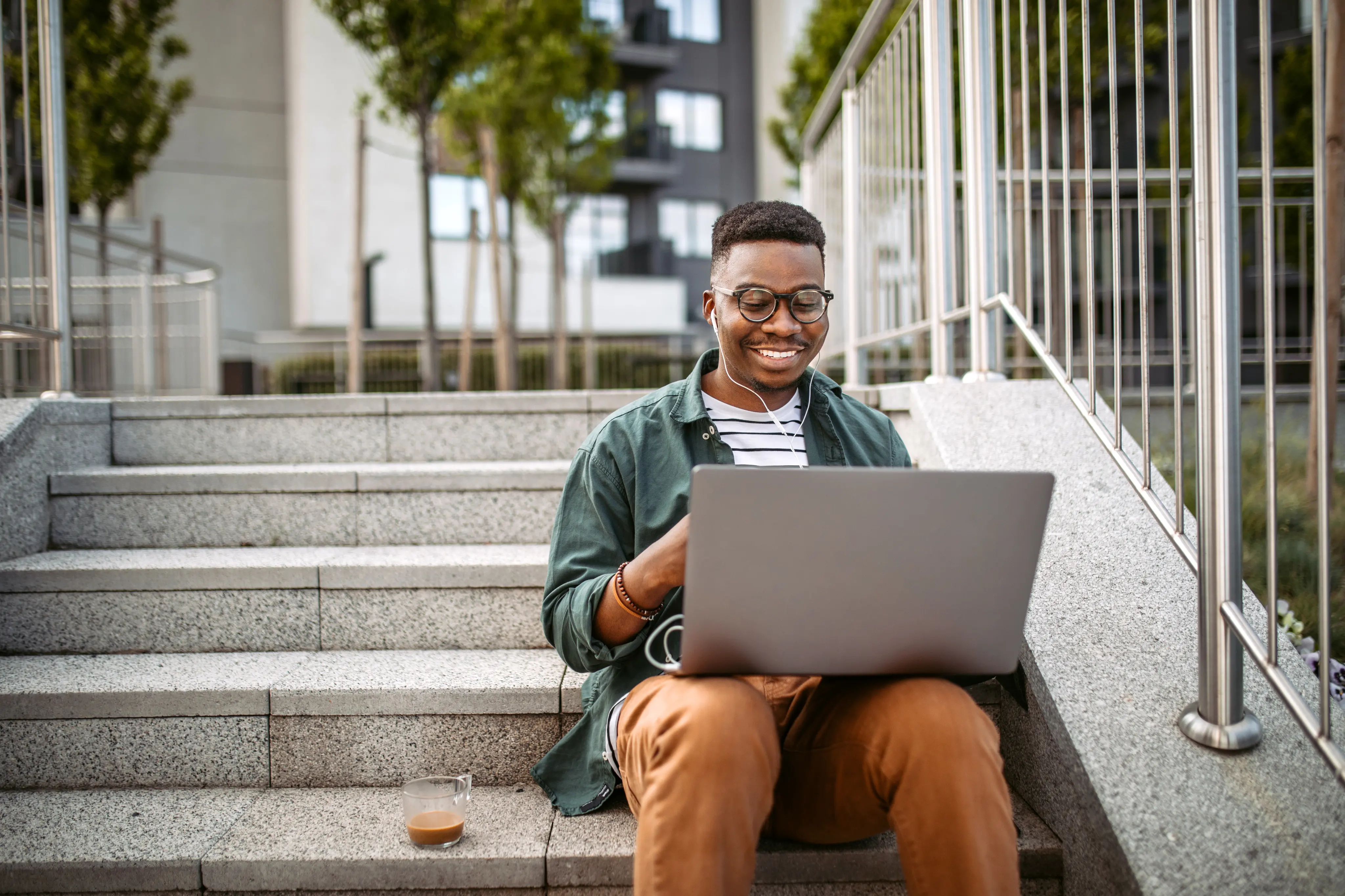 man working on laptop while sitting on stairs outside