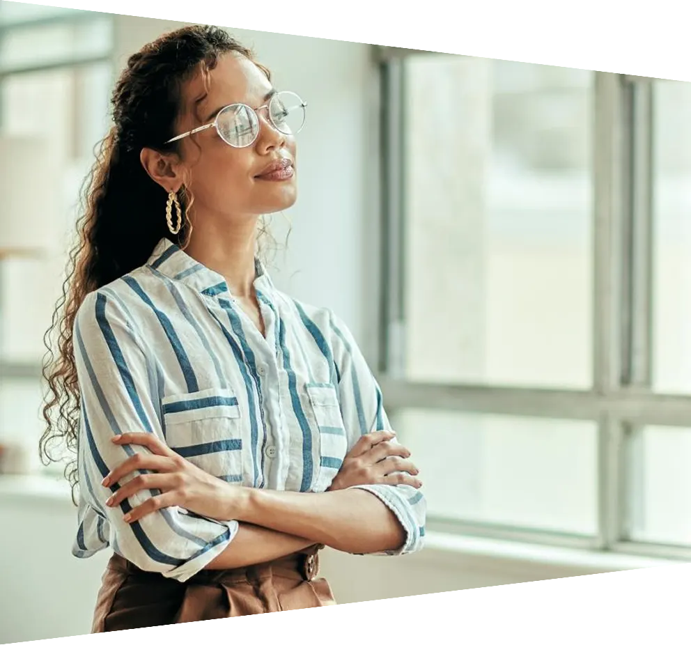 Young businesswoman with her arms crossed looking thoughtfully out of the window