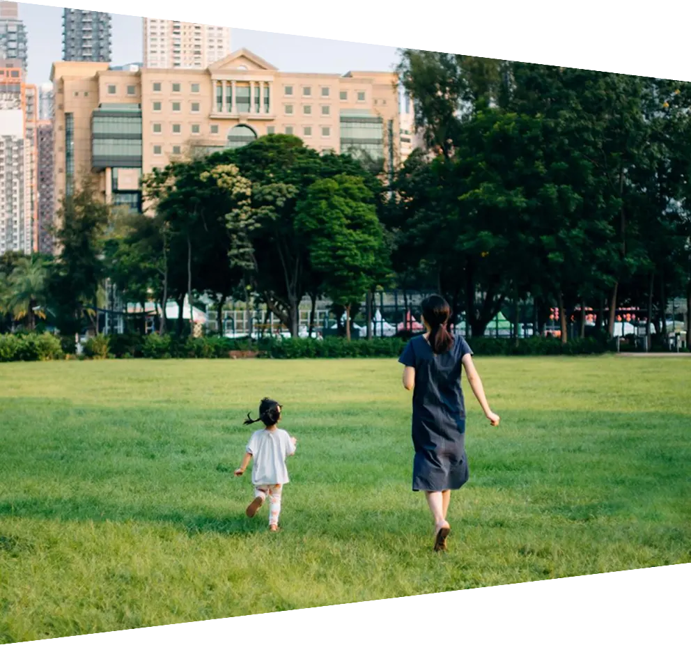 Rear view of happy young mother and daughter running around on grass