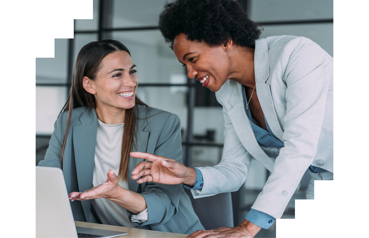 Two confident businesswomen in a meeting using laptop and discussing business strategy