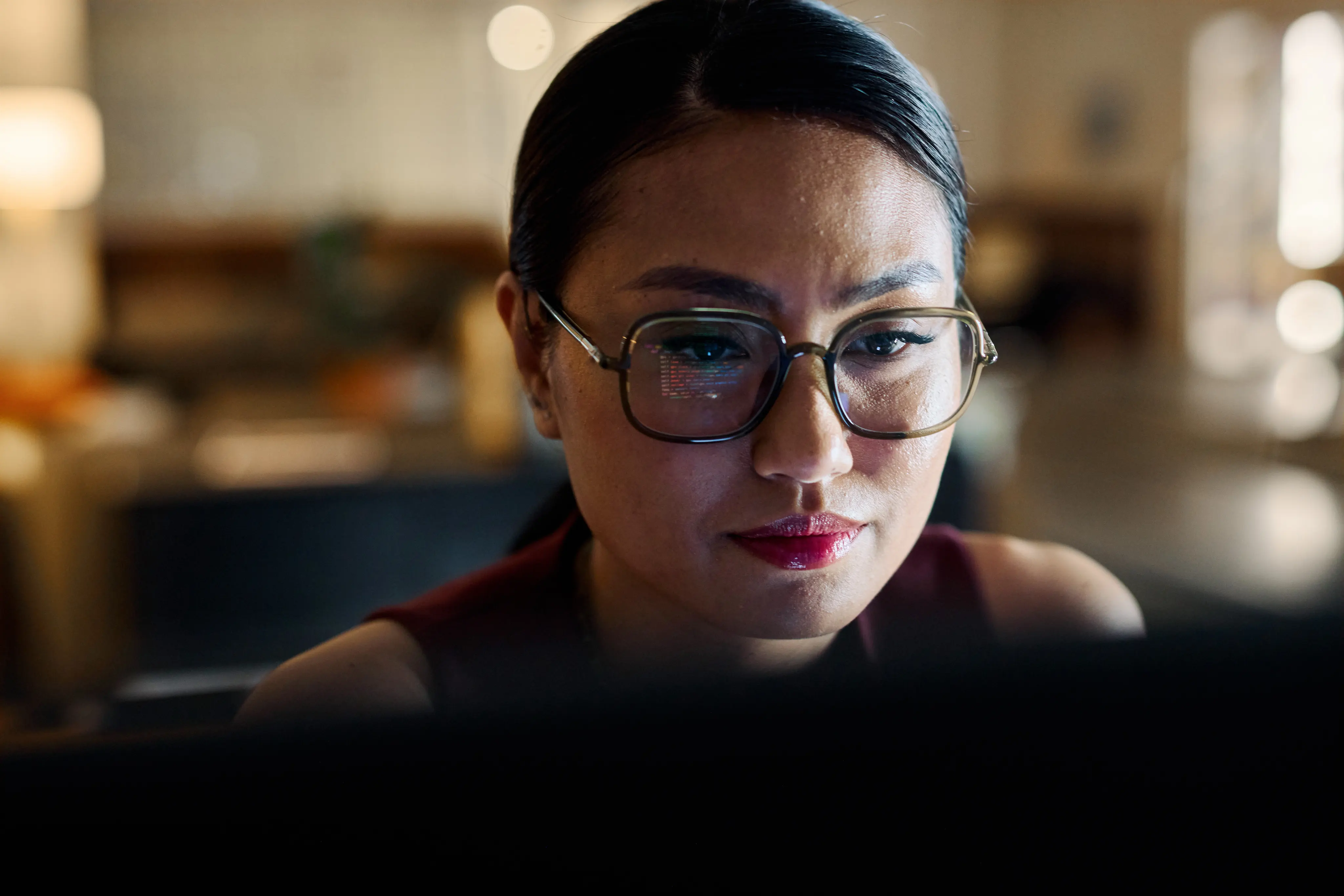 Woman wearing glasses focusing on illuminated computer screen