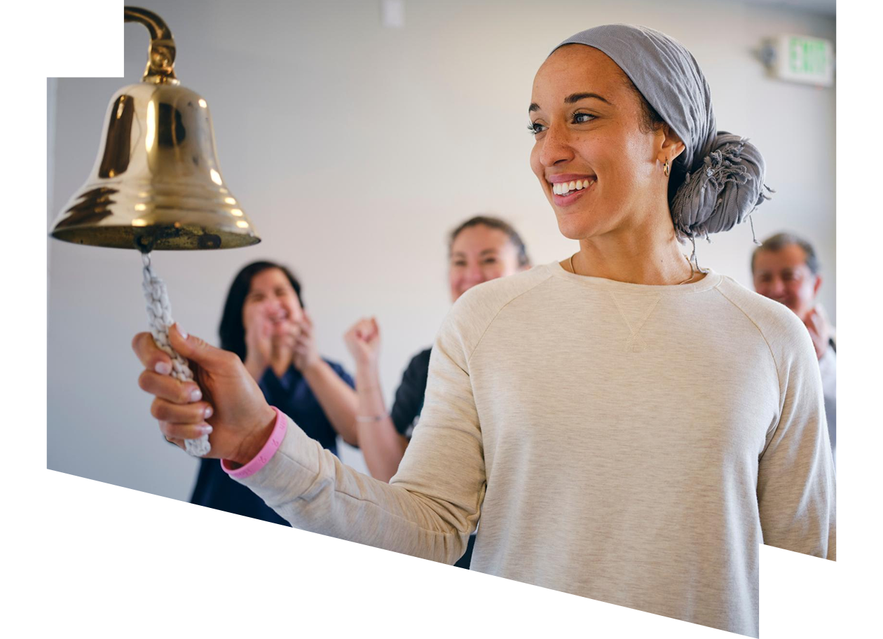 Adult woman chemotherapy patient finishing treatment with a ceremonial bell ring