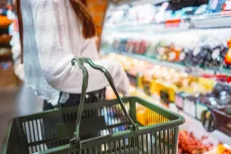 A woman chooses fresh fruits from an organic food display rack in the supermarket produce section