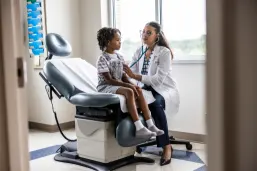 Female doctor listening to a young girl's heartbeat in an examination room