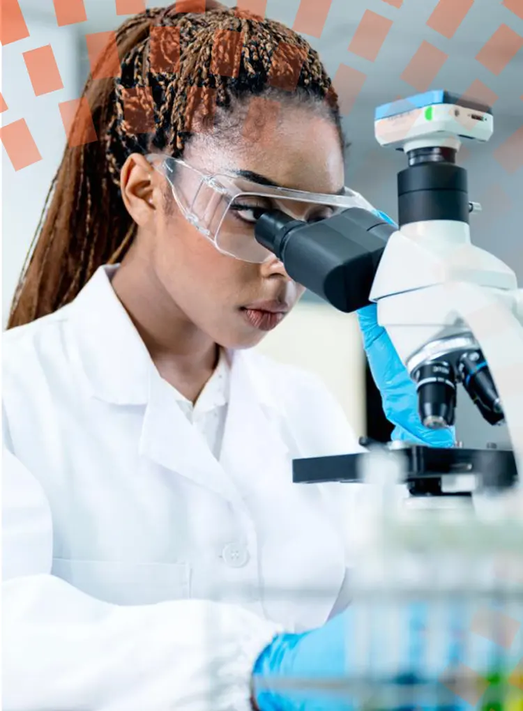 A female scientist conducting research on a sample though a microscope in a pharmaceutical laboratory