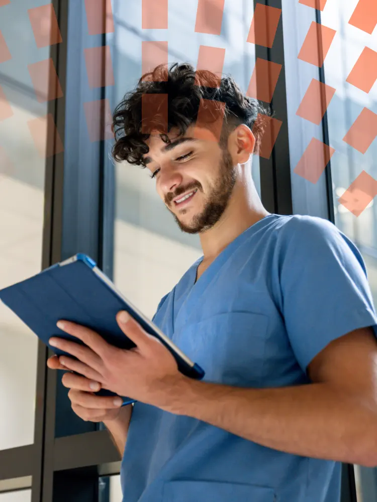 Enfermero joven sonriendo y mirando hacia abajo una tableta