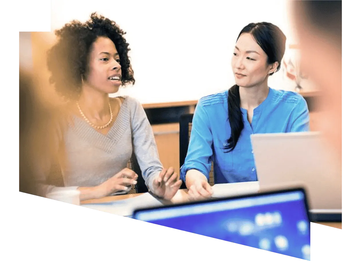 Woman having a conversation with another woman while sitting on a desk