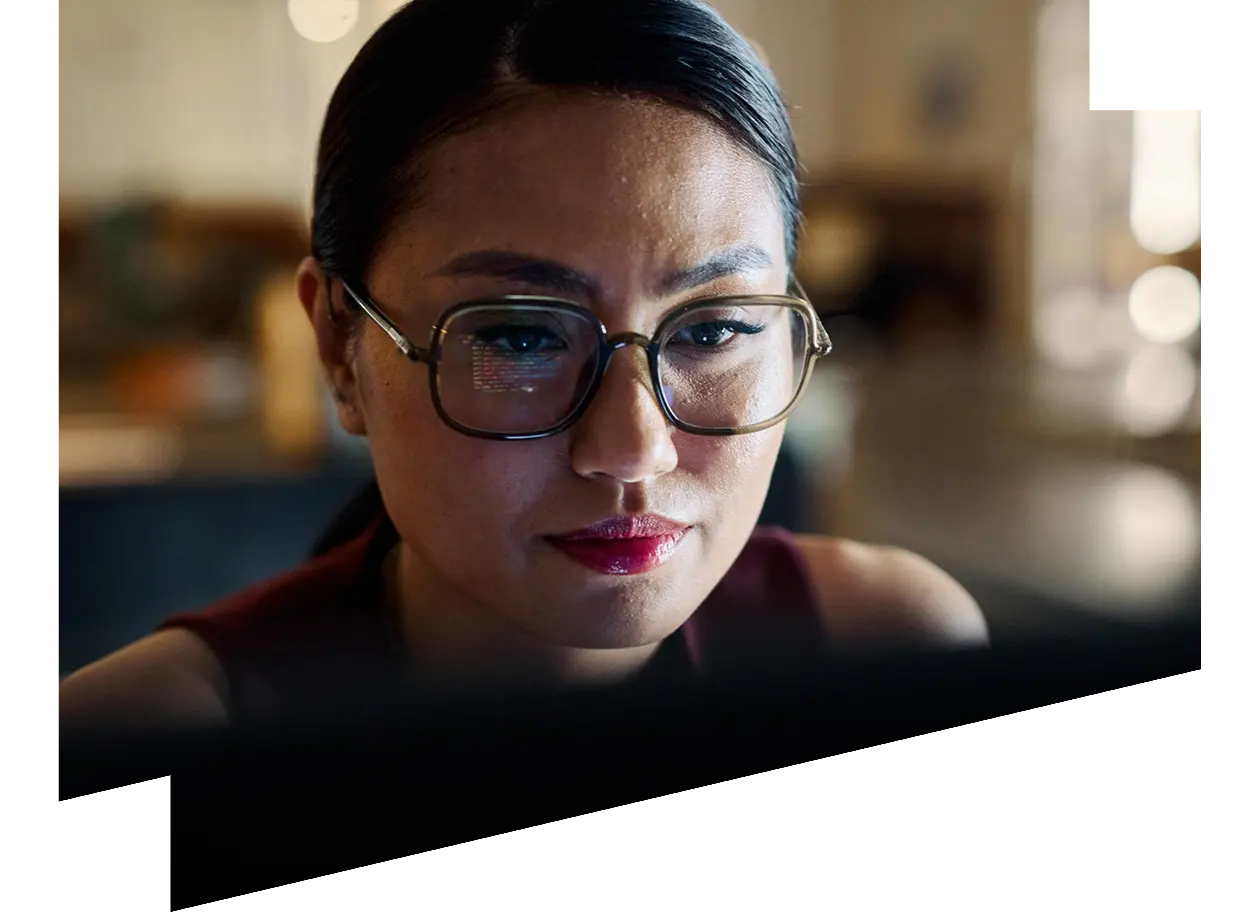 Woman wearing glasses focusing on illuminated computer screen
