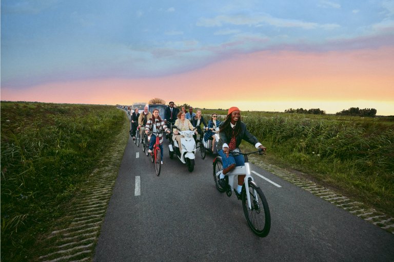 Un groupe de personnes roule ensemble sur une route de campagne à bord de différents types de véhicules