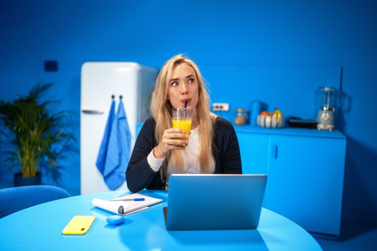 nadenkende vrouw achter laptop drankje drinkend