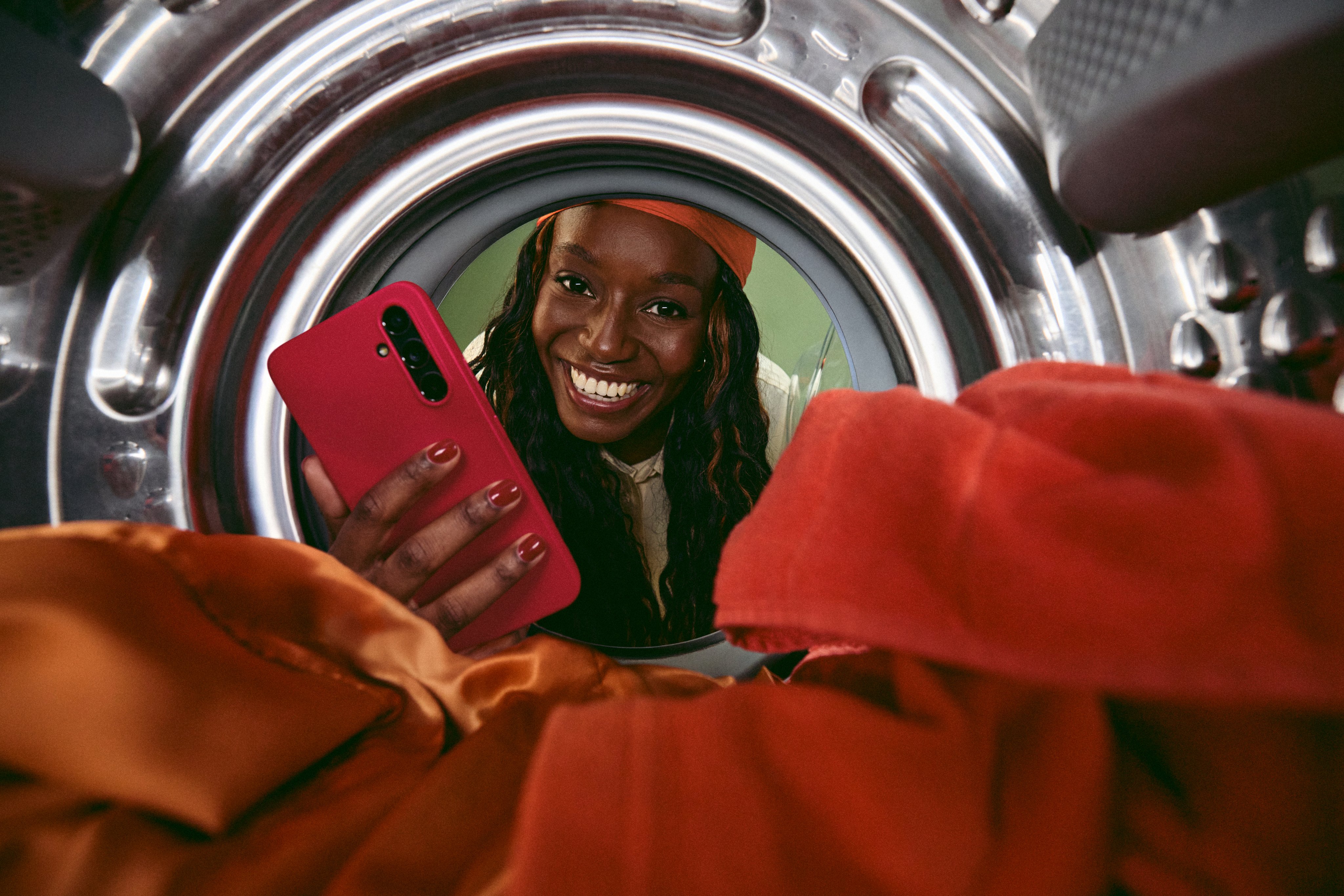 Vrouw met smartphone kijkt in de wasmachine