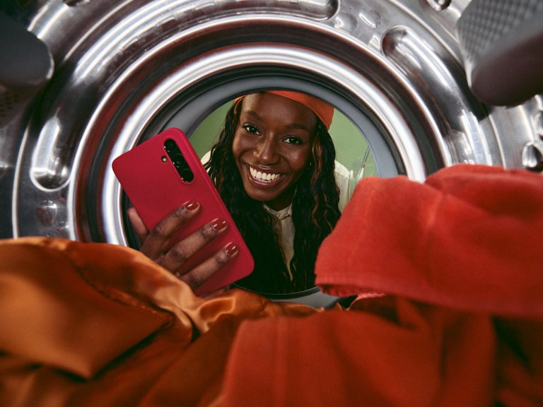Vrouw met smartphone kijkt in de wasmachine