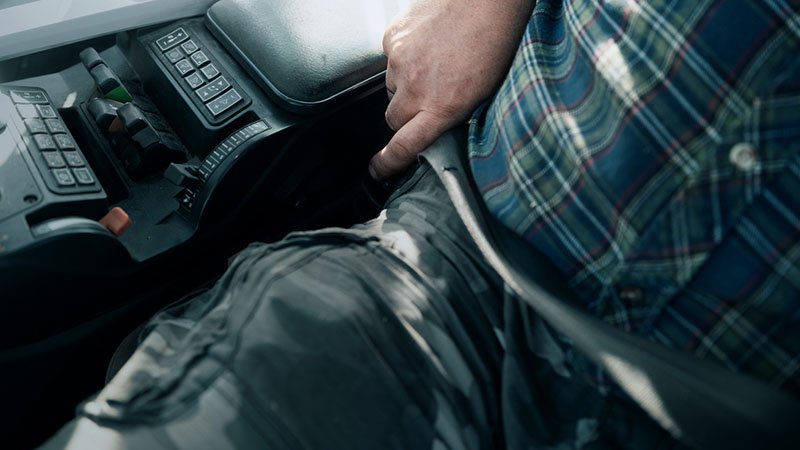 Nærbilde av at noen fester på seg setebelte i en traktor.