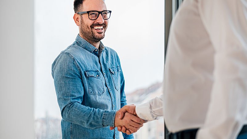 To menn i skjorter håndhilser på hverandre. 