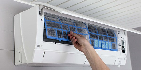 Hånd som løsner et filter fra en varmepumpe