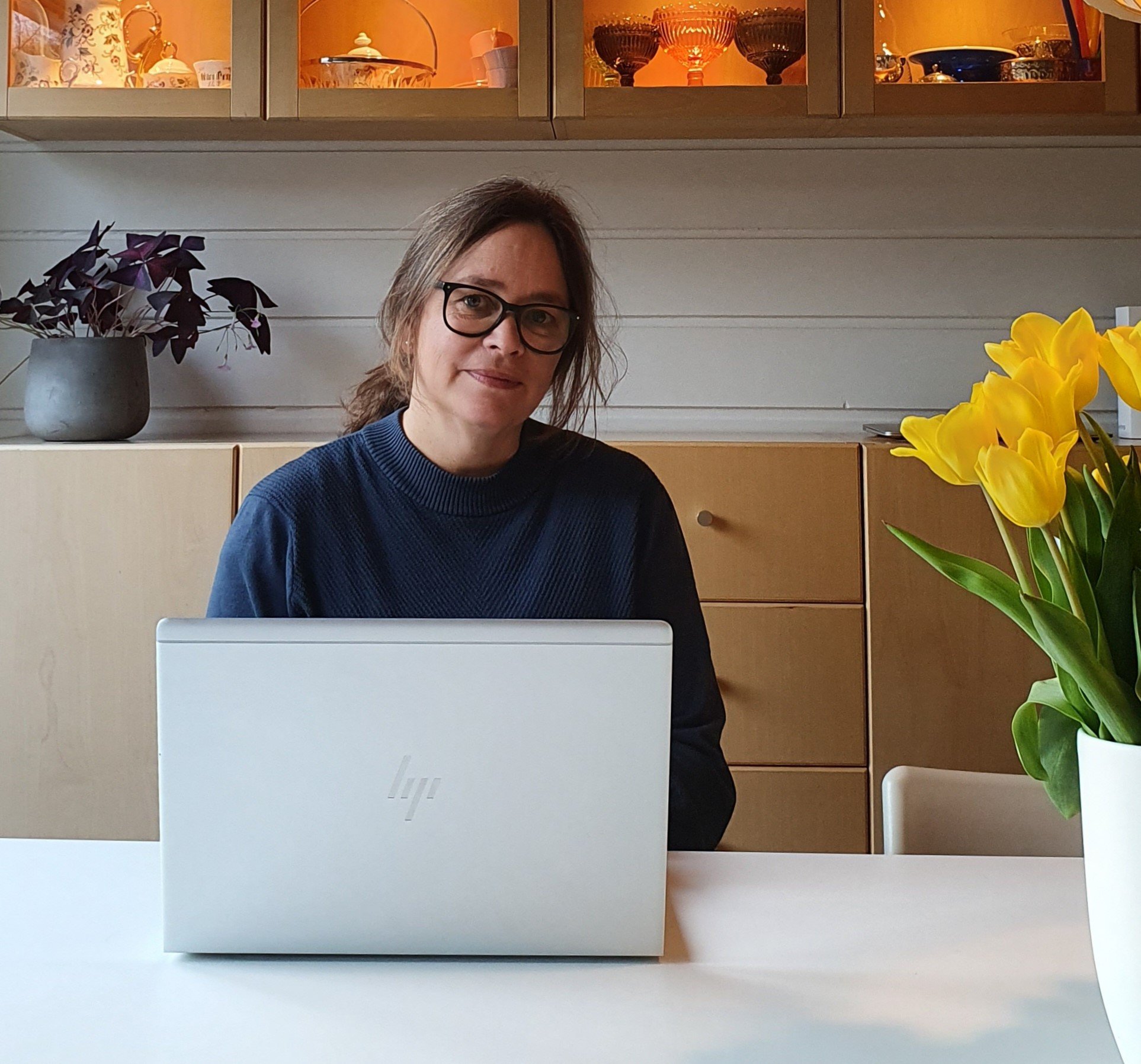 Kristin Gisholt sitter på kjøkkenet sitt foran en laptop. 