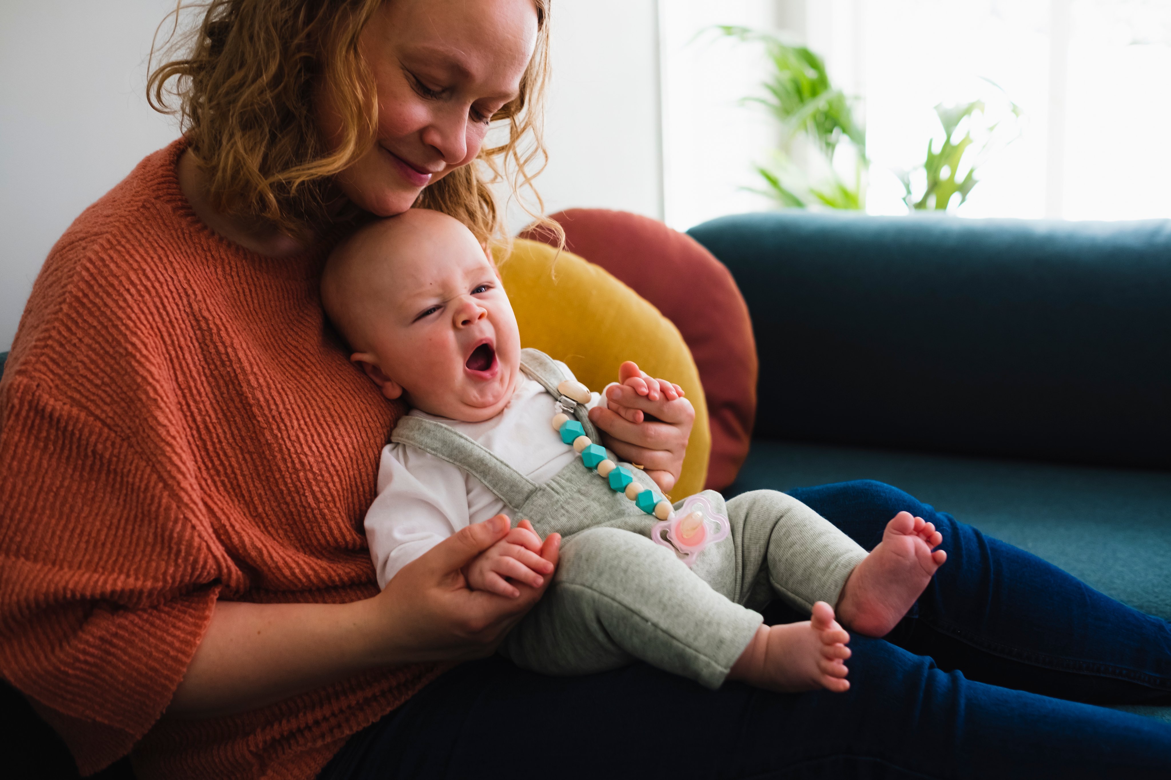 En kvinne sitter på en sofa og holder en baby.