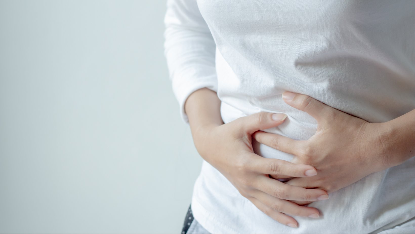 Kvinne holder seg til magen.