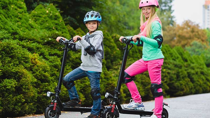 To barn på elsparkesykkel.