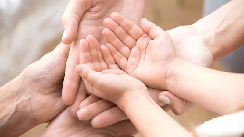 Barnehender ligger i to par med voksenhender