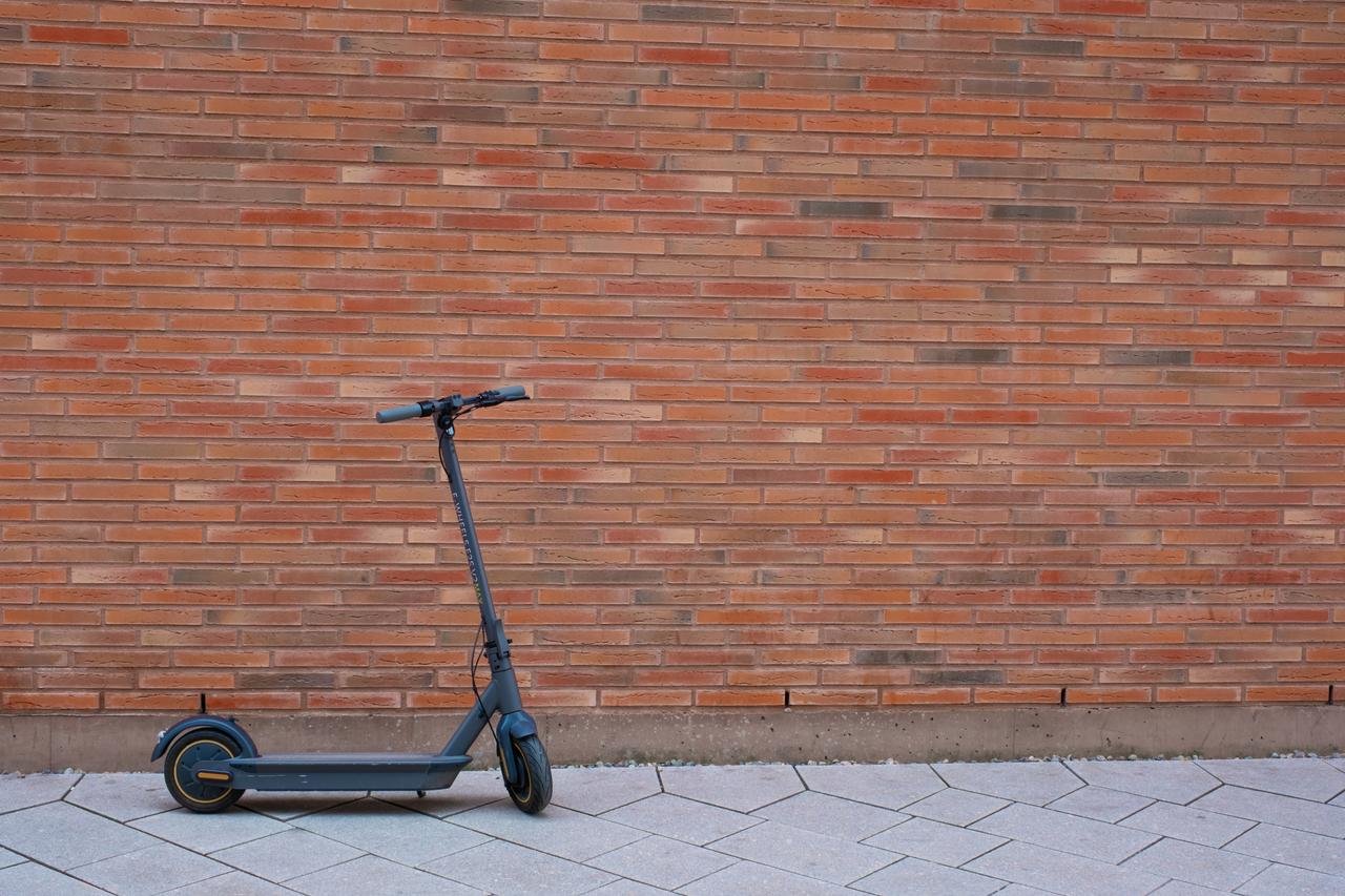 Elektrisk sparkesykkel stående foran en murvegg