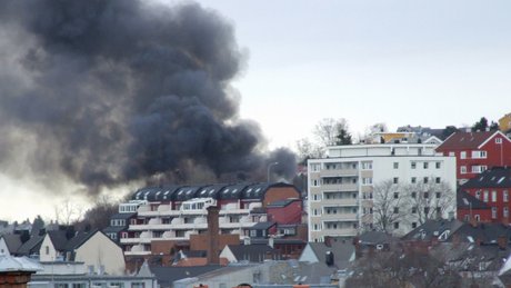 Det kommer sort røyk fra en boligblokk.