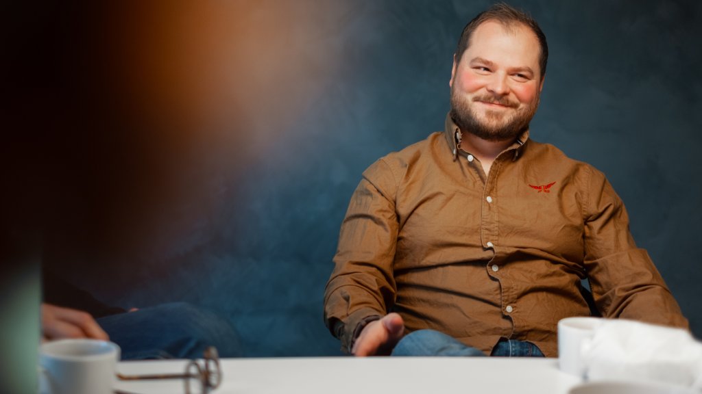 Mann i skjorte som sitter i et møterom