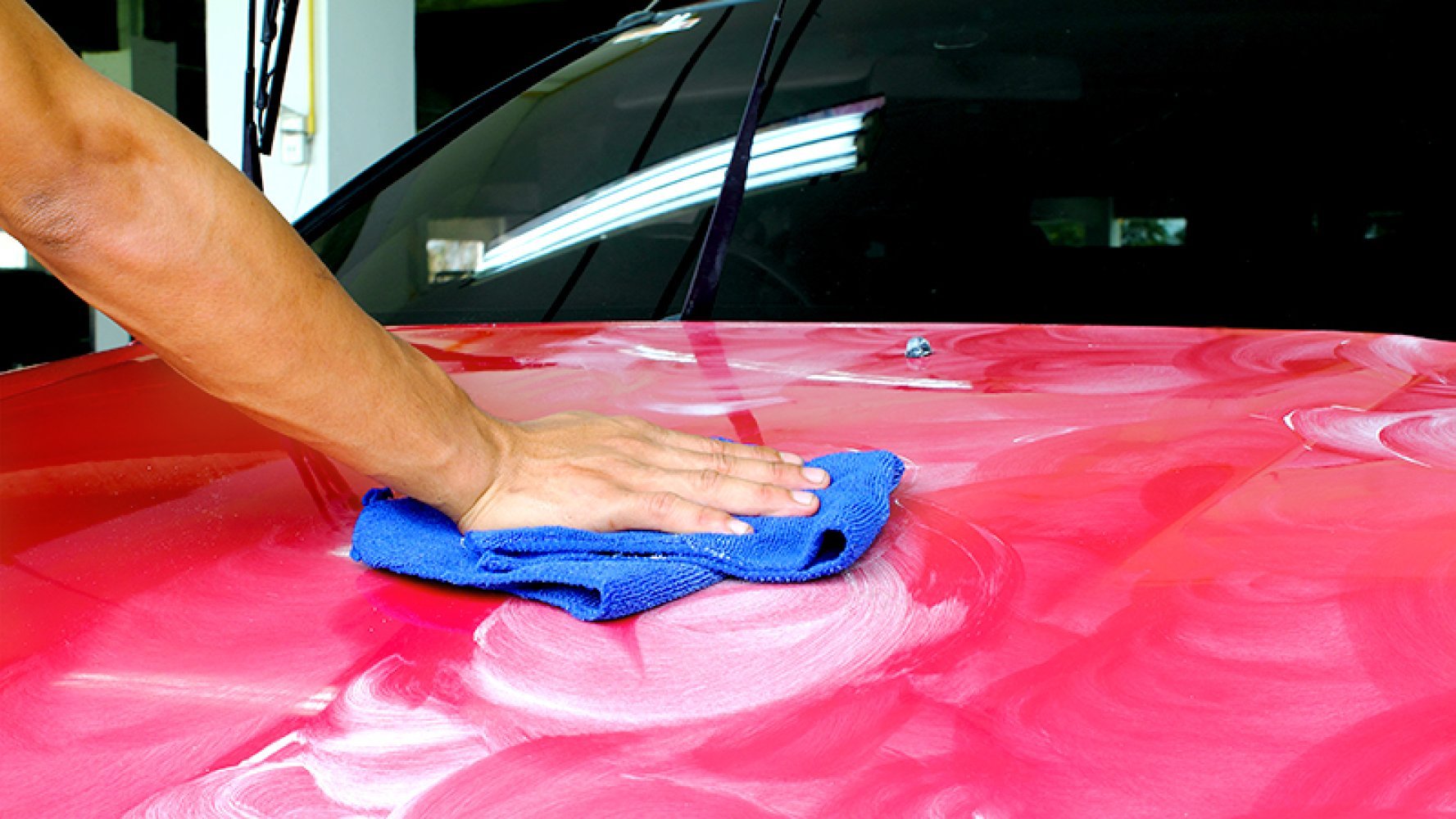 En person polerer panseret på en bil med en mikrofiberklut.