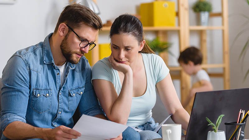 Et ektepar sitter i en stue og ser på forsikringsdokumenter.