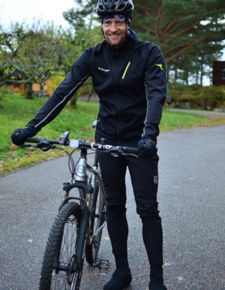 Petter Hveem står ved siden av sykkelen sin i full oppkledning, ed sykkelhjelm og varme, tekniske klær og hansker. 