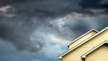 Et hus med mørke faretruende skyer i bakgrunnen.