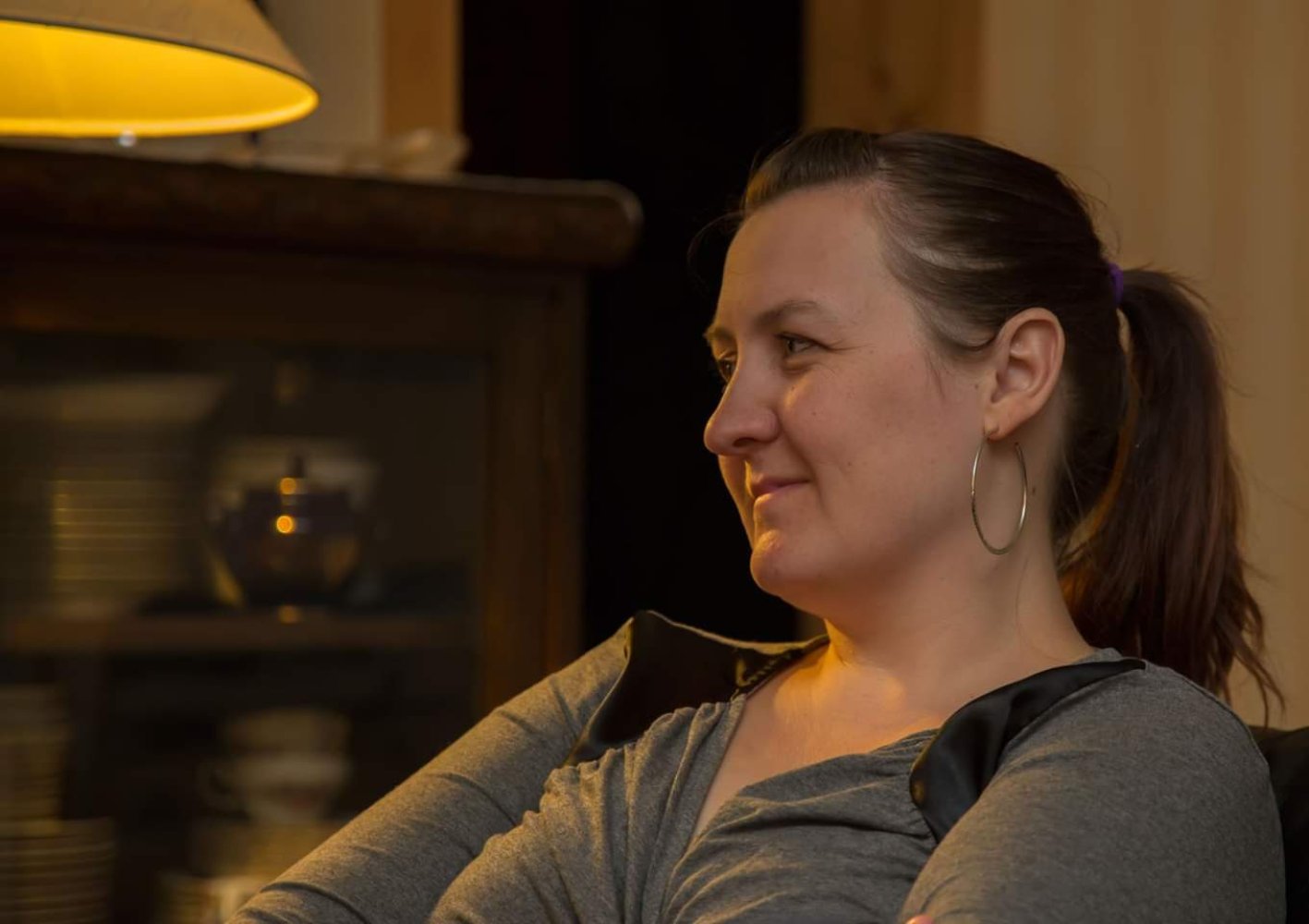 Nærbilde av May Jønsson som sitter i en stue og ser tankefull ut.