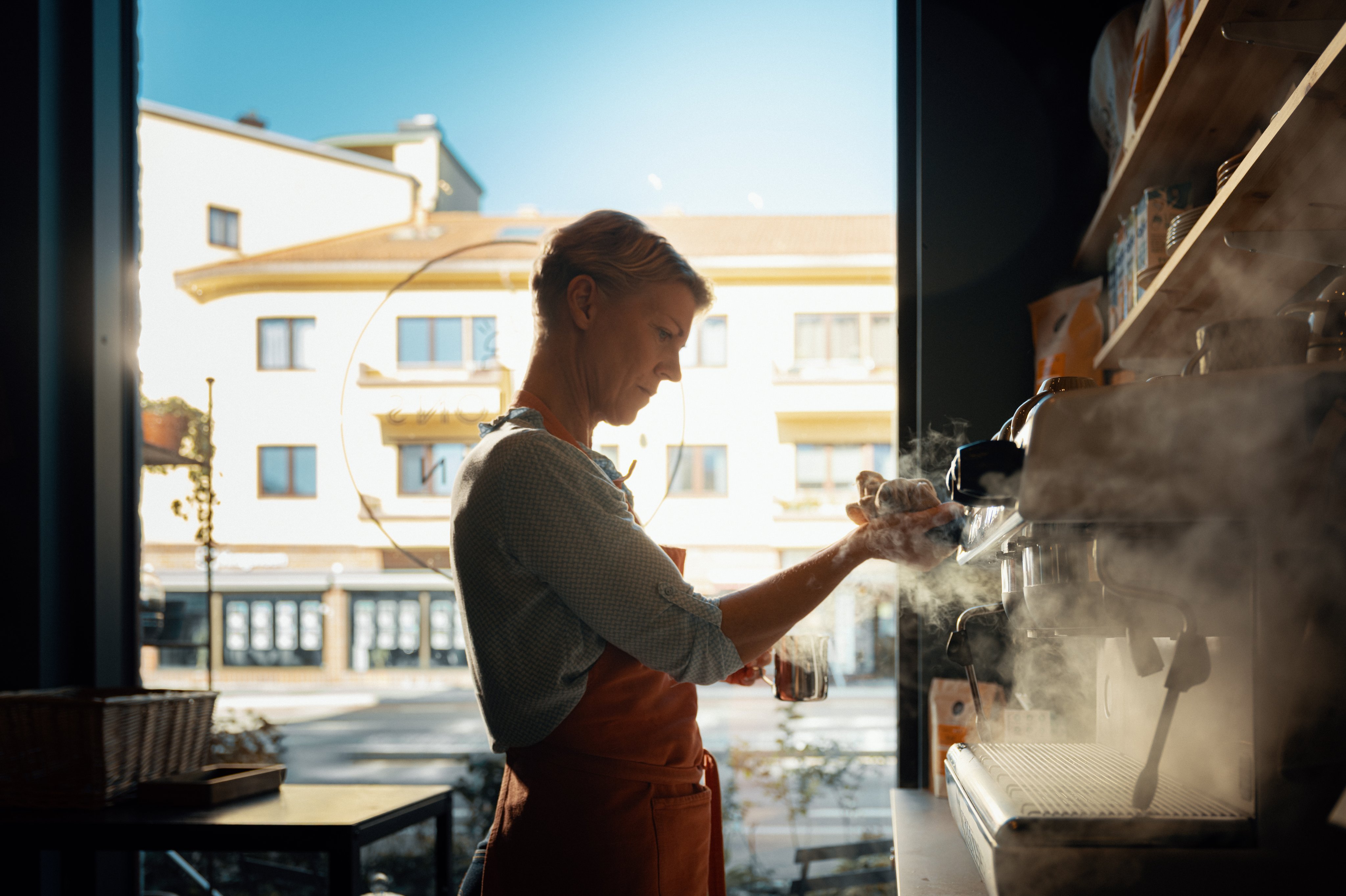 Ansatt som jobber med kaffemaskinen på en kafé. 