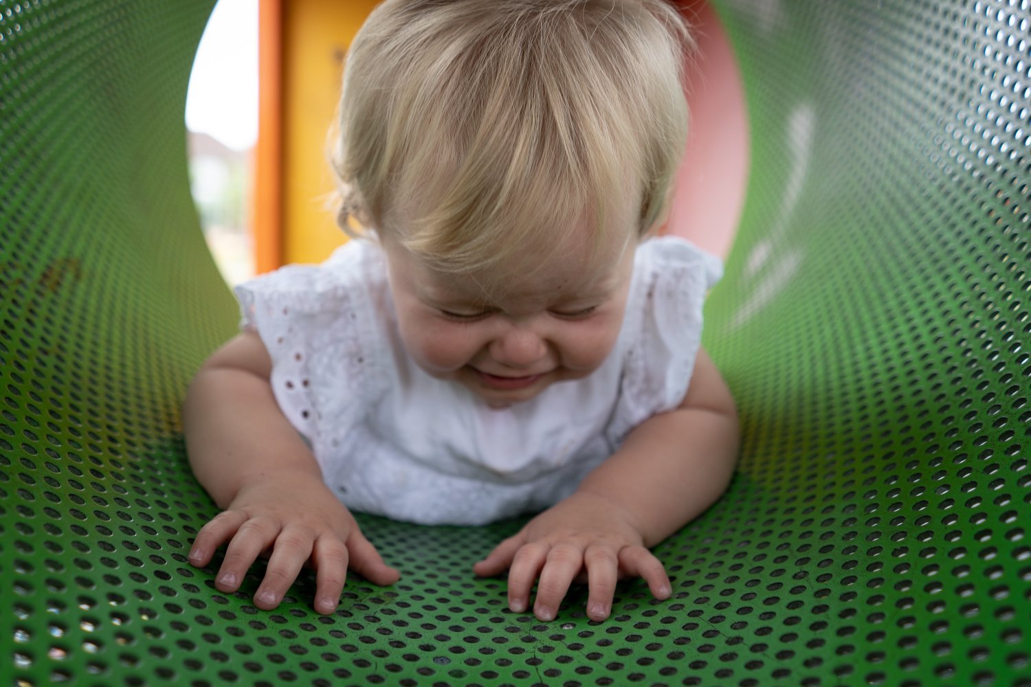Barn kryper gjennom en perforert tunnel på en lekeplass