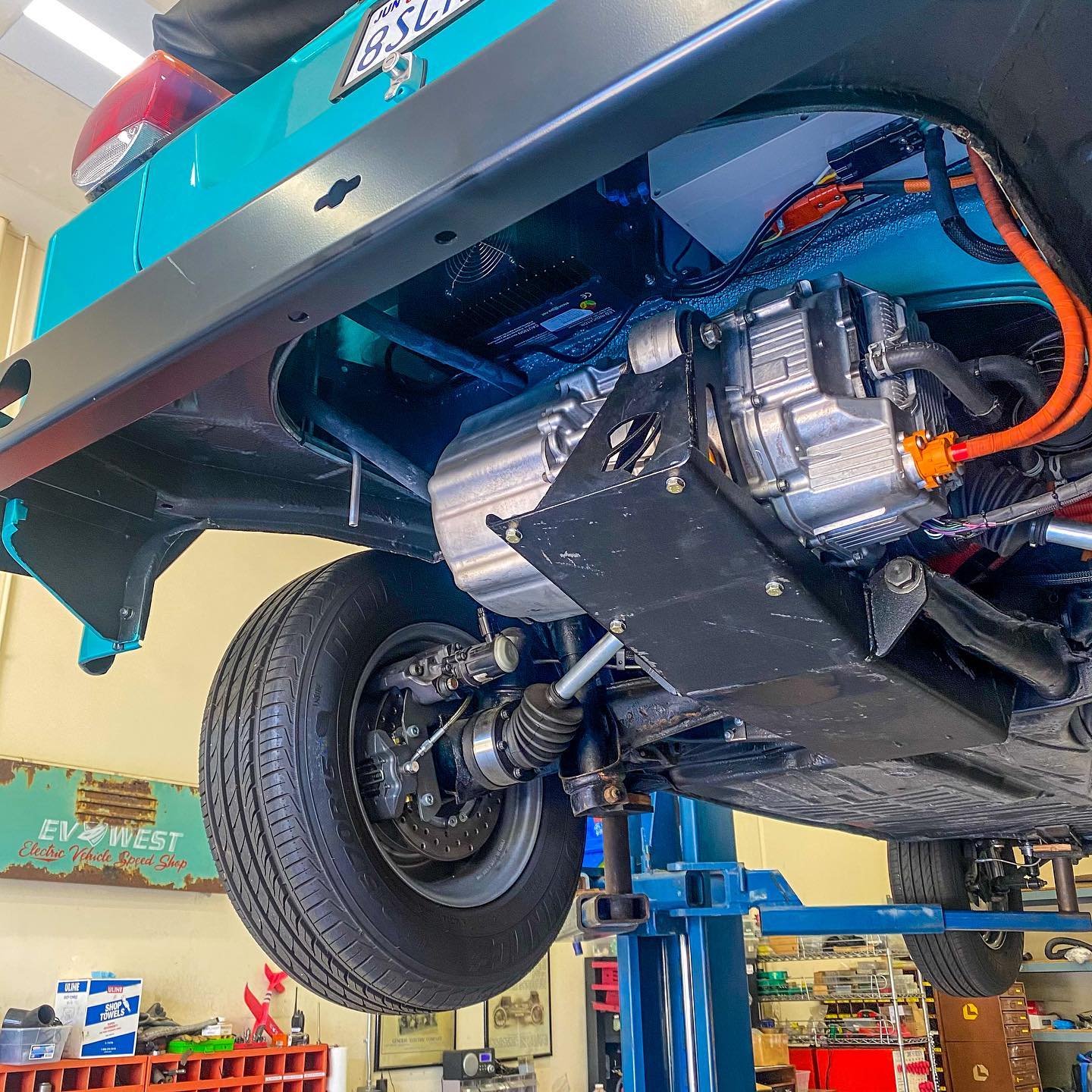 Undersiden av en varebil med synlig elektrisk motor, høyspentkabler og hjuloppheng.