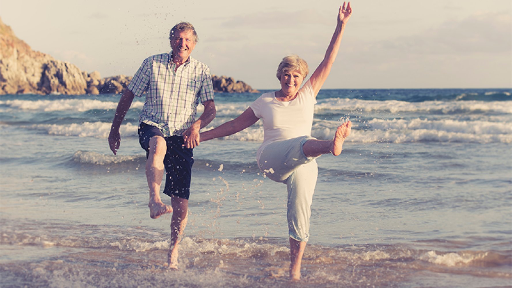 Et eldre par leker i vankanten på en strand.