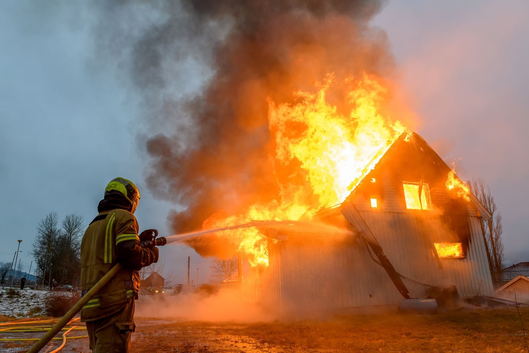 En brannkonstabel som slukker en boligbrann.