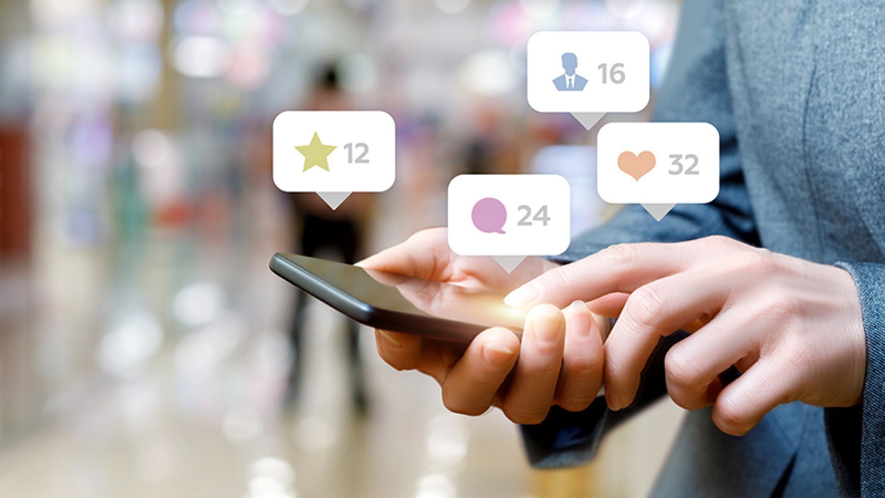 Mobil liggende i en hånd mens den andre scroller på den og grafikk som visualiserer at det kommer det likes og kommentarer