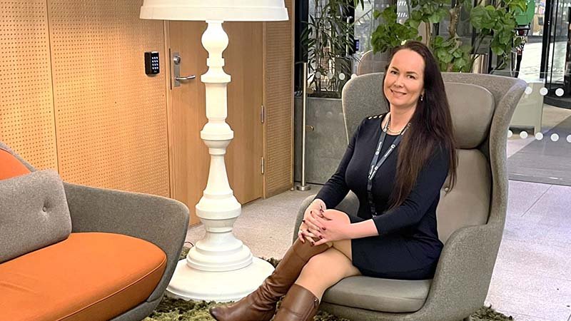 Elin Schjelderup sitter smilende i en sofastol i Gjensidiges lokaler