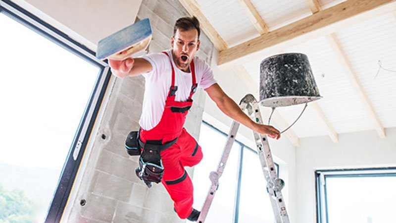 En murer i røde bukser faller fra en gardintrapp.