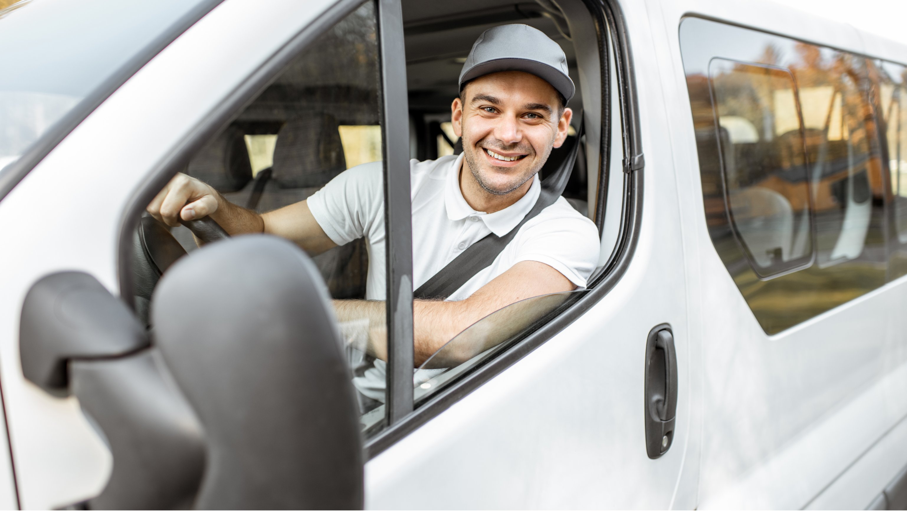 Smilende mann bak rattet i en arbeidsbil