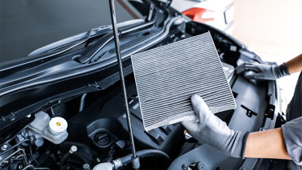 Et ac-filter blir tatt ut fra bilens motorrom.