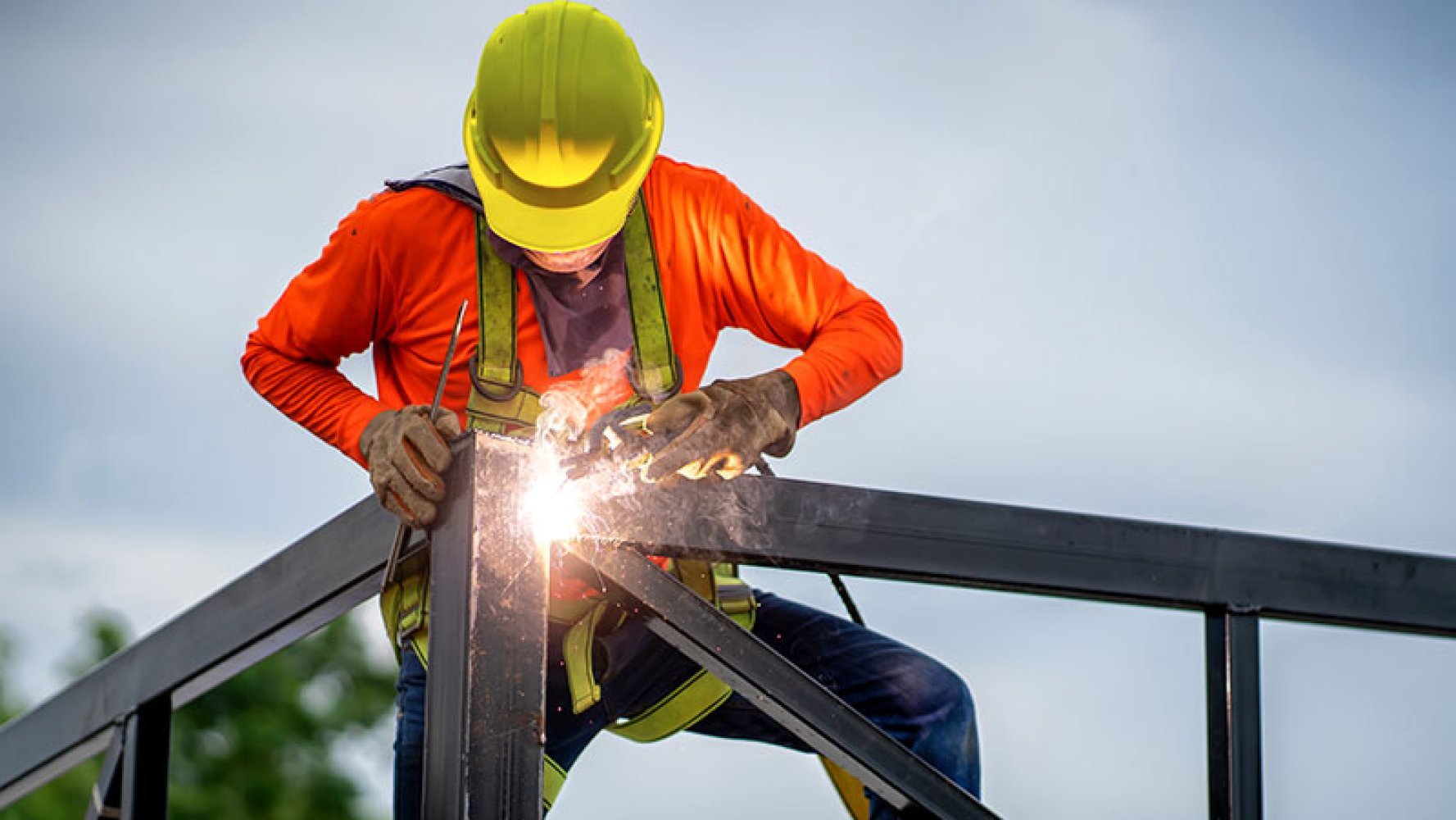 En arbeider sveiser stålbjelker.