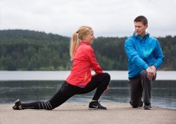 Dame tøyer hofteleddsbøyer mens trener ser på